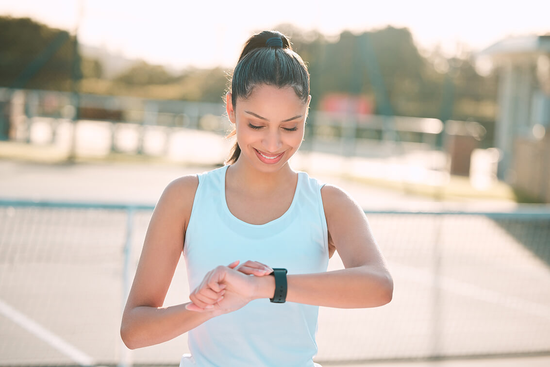 A woman working out outside and looking at her digital watch