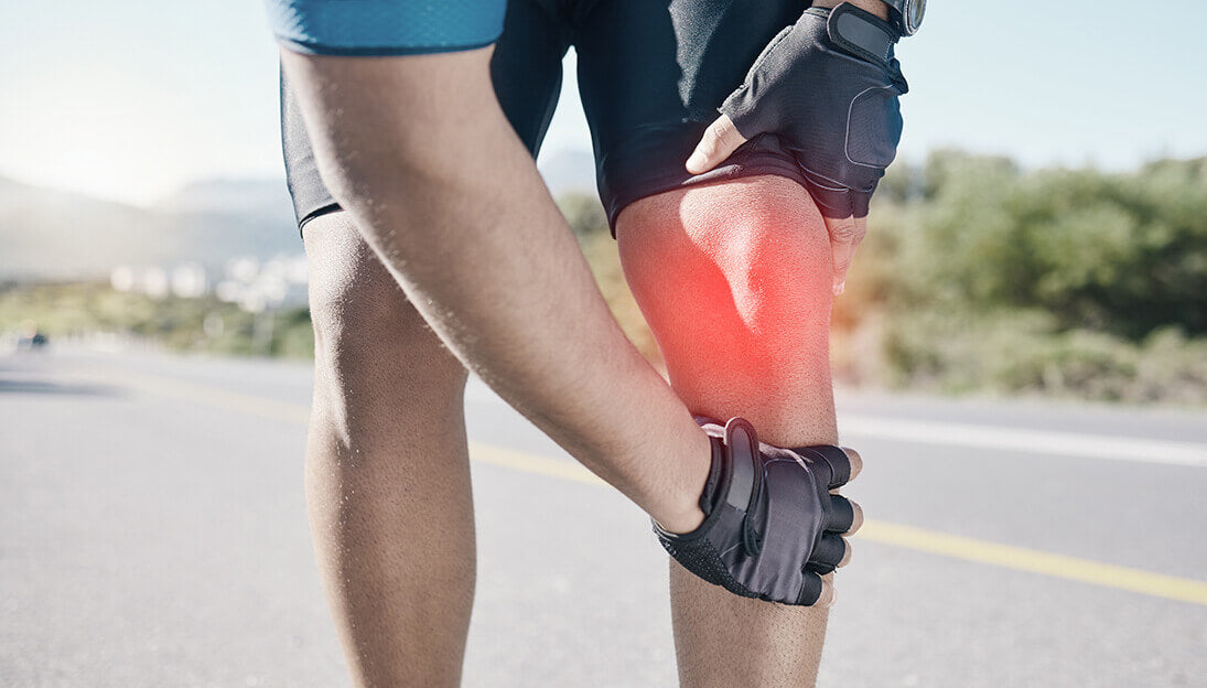 A cyclist holding his knee due to knee pain